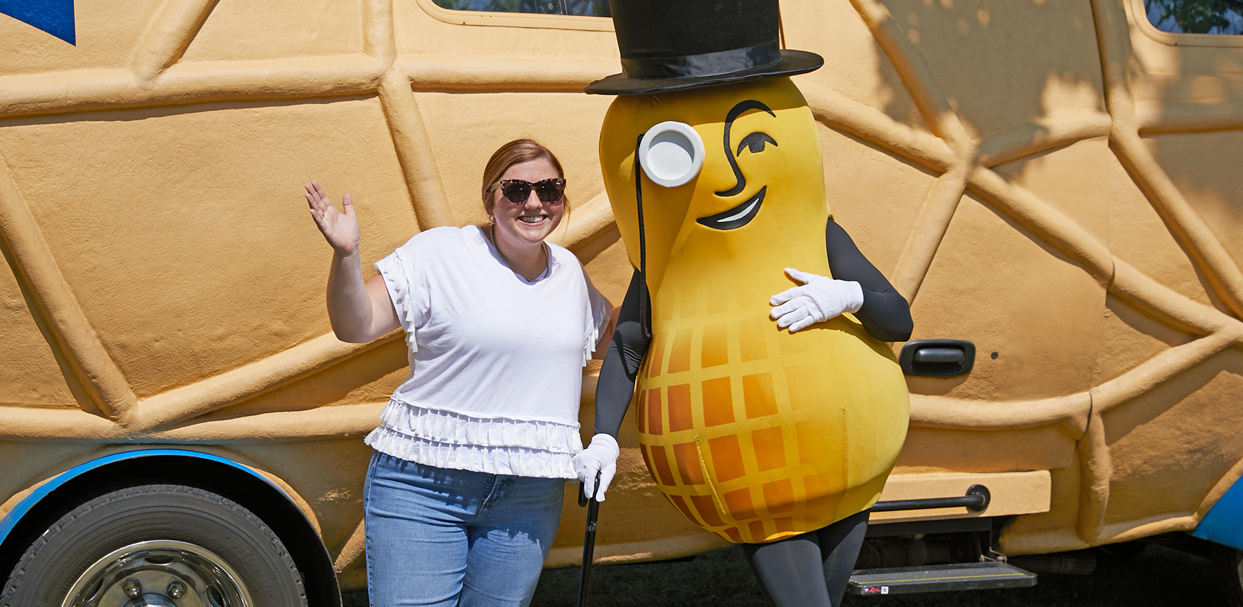 Mr Peanut standing with a woman wearing a white t-shirt in front of the Nutmobile