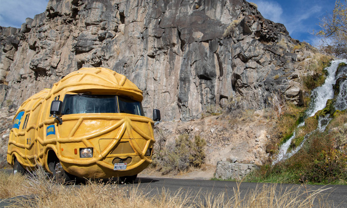 The Nutmobile driving on a road in front of a tall mountain