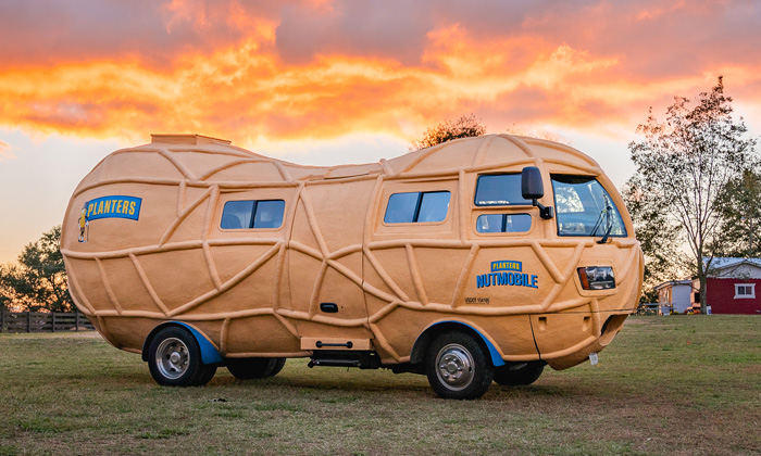 the Nutmobile parked on grass in front of an intense sunset